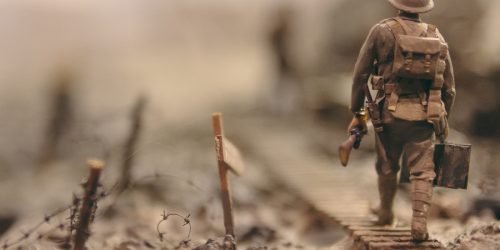 soldier walking on wooden pathway surrounded with barbwire selective focus photography